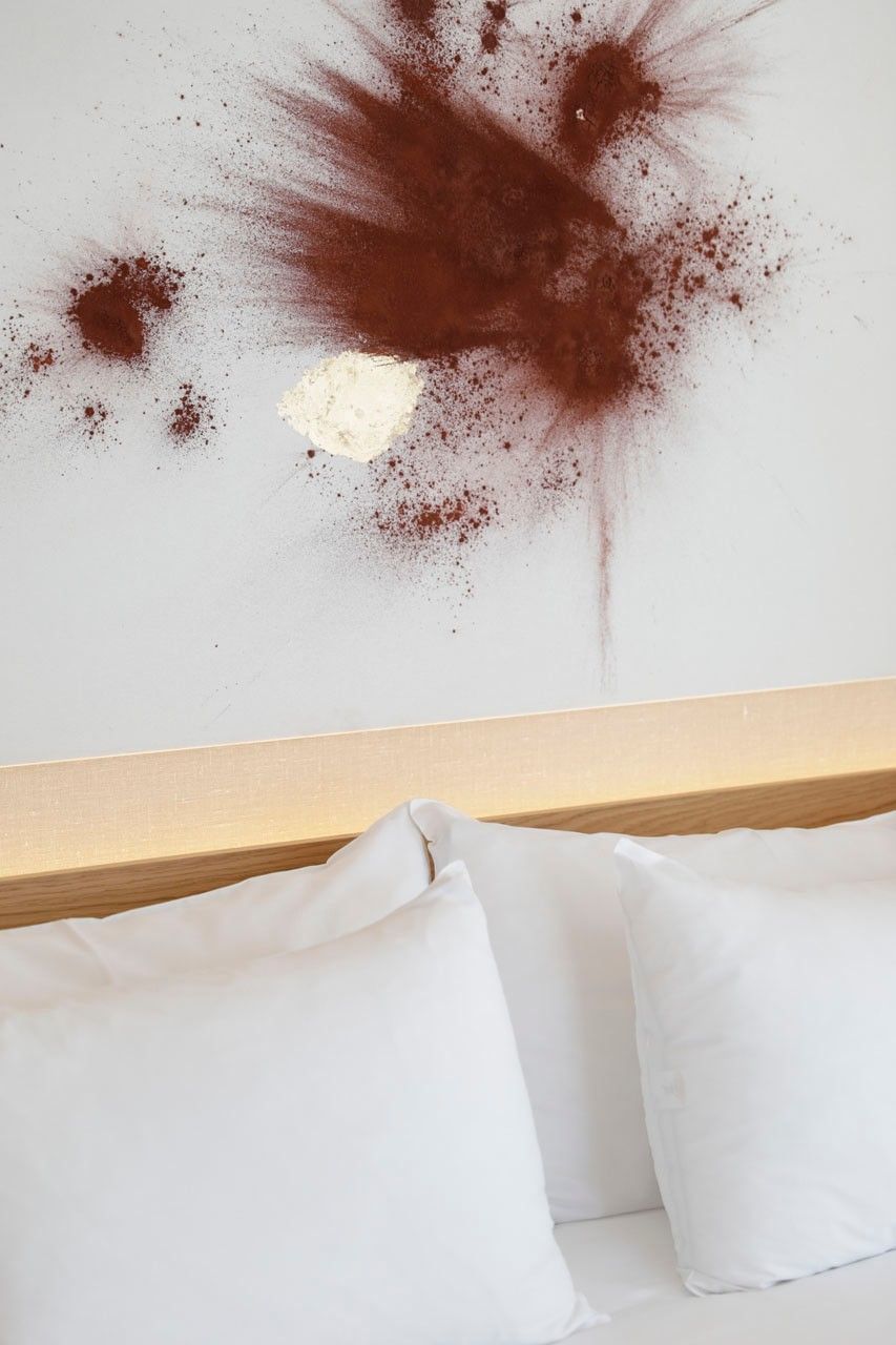 Lit avec oreillers blancs devant un mur avec taches de cacao à Ibiza Gran Hotel