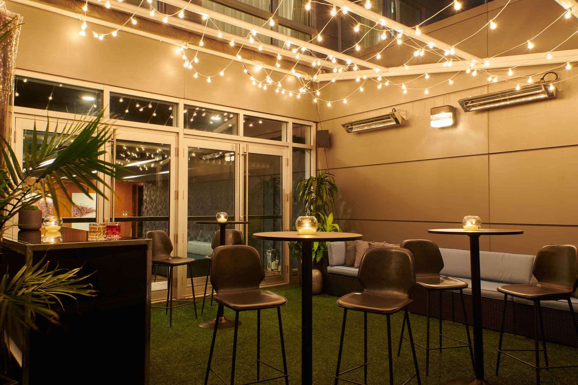 Vibrant outdoor bar and lounge at Warwick Hotels and Resorts, illuminated by string lights for an evening social event
