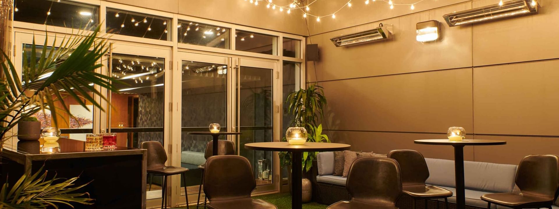 Bar et salon extérieur animé au Warwick Hotels and Resorts, illuminé par des guirlandes lumineuses pour une soirée sociale.