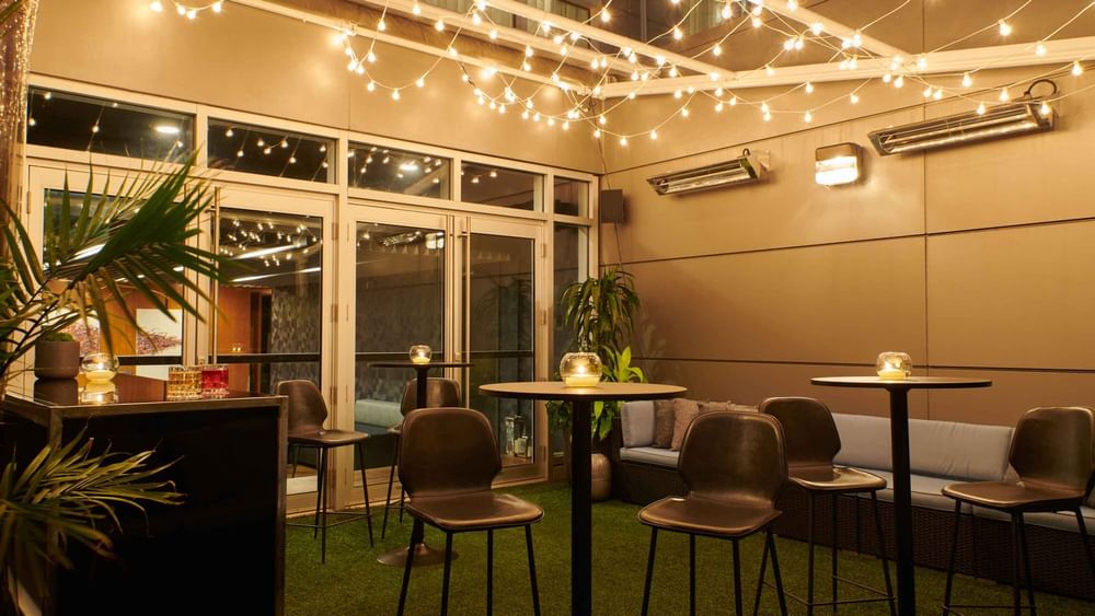 Bar et salon extérieur animé au Warwick Hotels and Resorts, illuminé par des guirlandes lumineuses pour une soirée sociale.