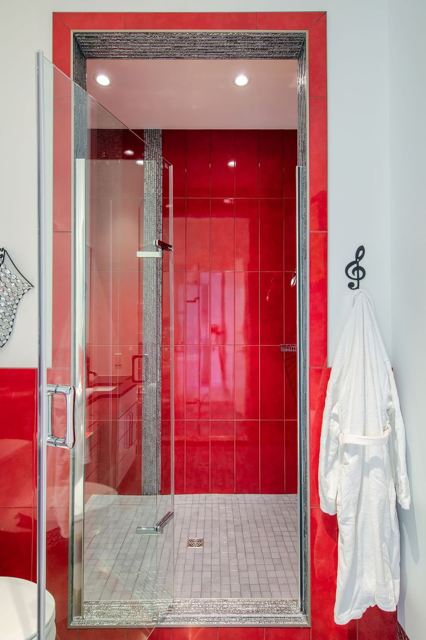 red tile shower walk in shower with a robe hanging beside