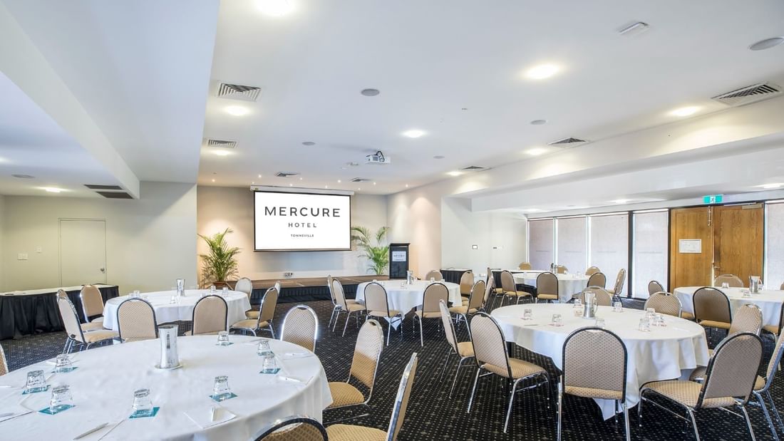 Crystal Room with cabaret table setup featuring a projector screen and elegant decor at Mercure Hotel Townsville