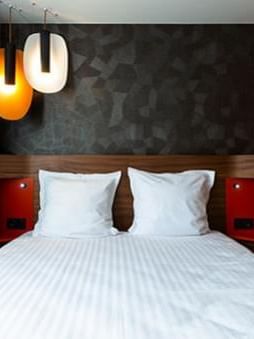 Comfy king bed with hanging lights at Oceania Hotels