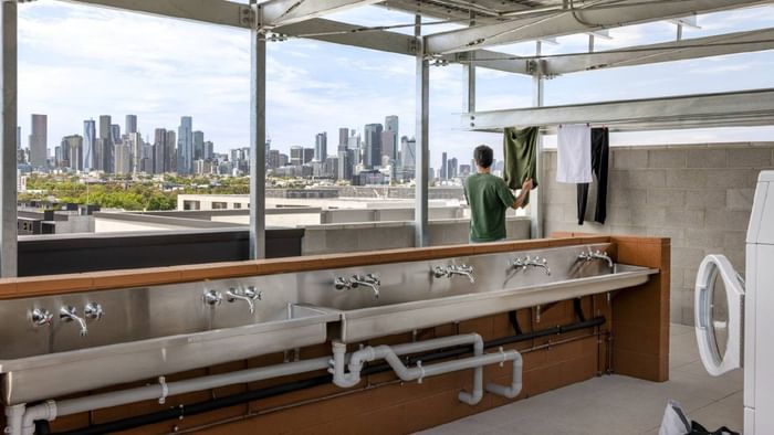 Modern laundry facility with stainless steel sinks and city skyline views at Swift Walk, Kensington