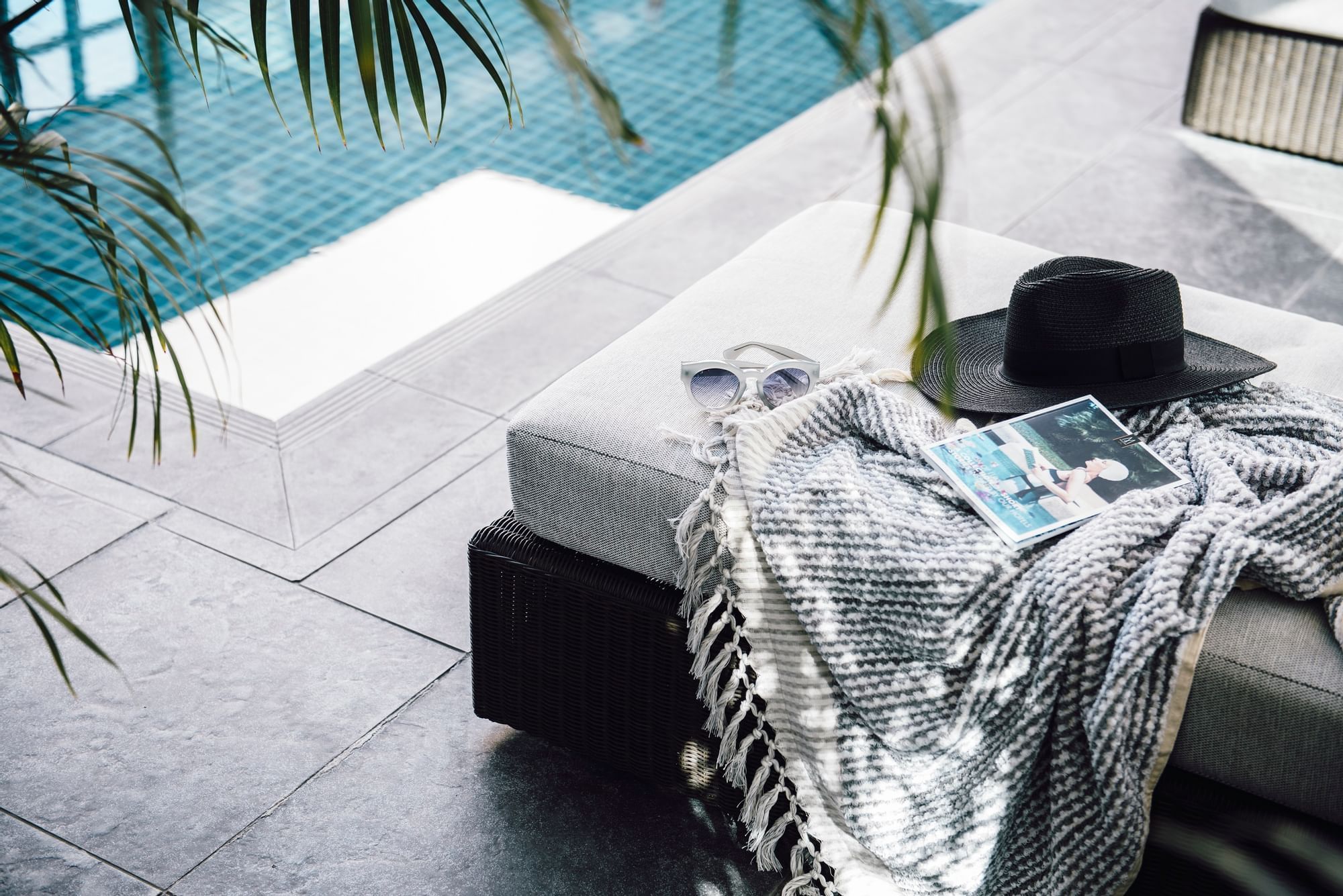 Blanket, book & hat on sunbed near pool at The Como Melbourne