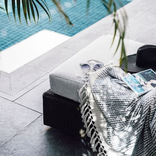Blanket, book & hat on a sunbed by the pool at Como Melbourne