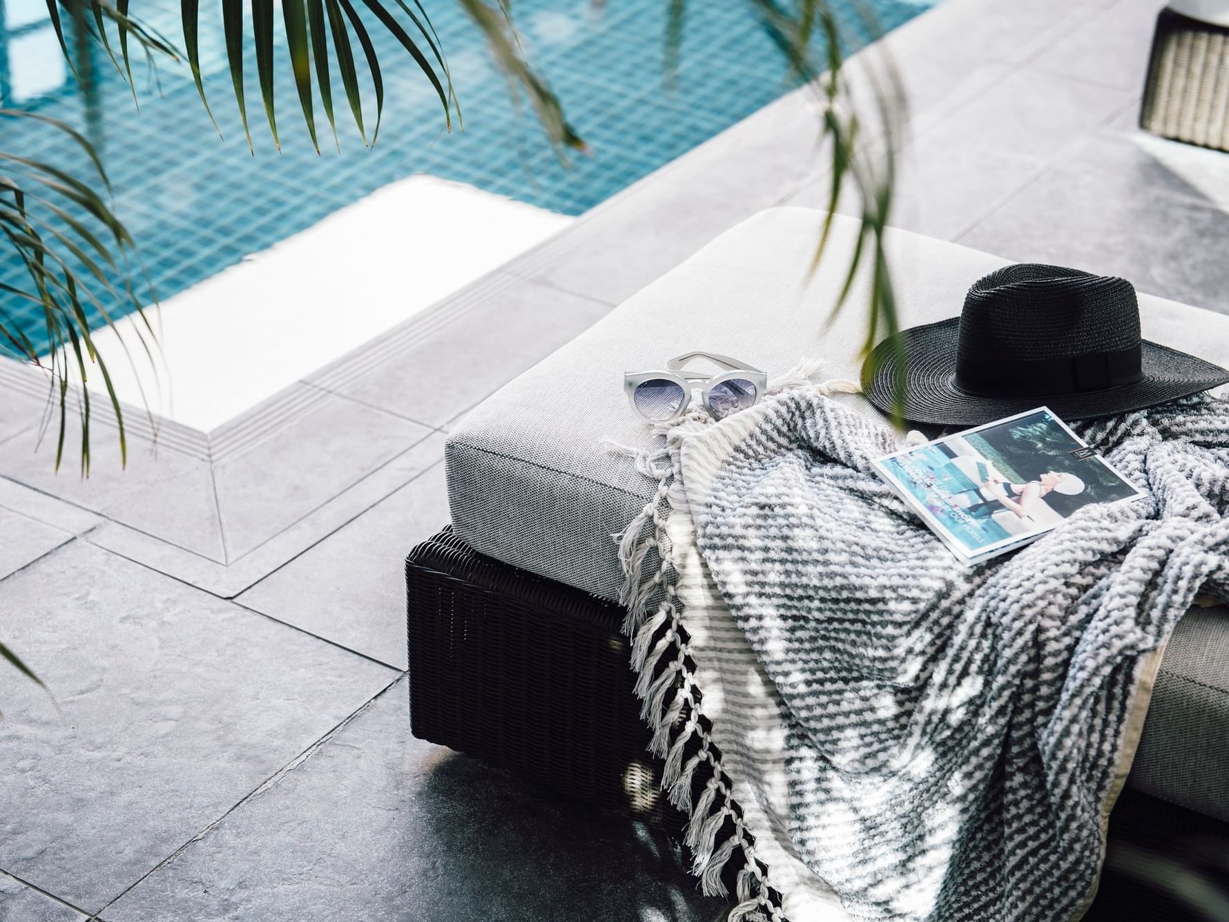 Blanket, book & hat on a sunbed by the pool at Como Melbourne