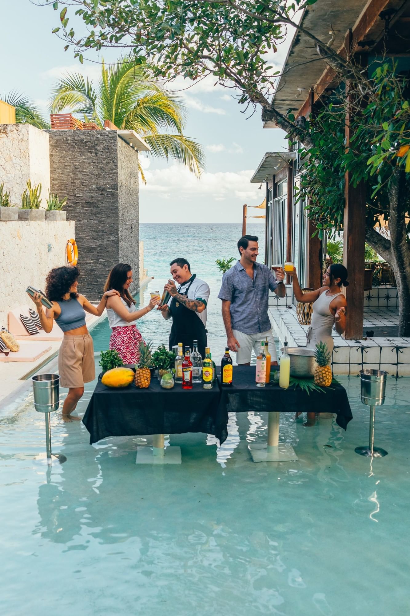 Friends learning to mix cocktails beside the infinity pool at Mi Amor in Tulum