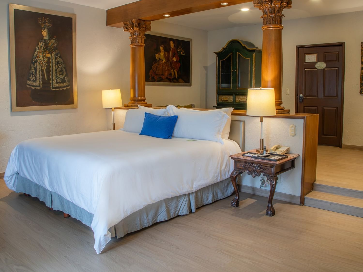 Spacious King Governor Suite with white bedding, ornate columns, and colonial artwork at Quinta Real Guadalajara