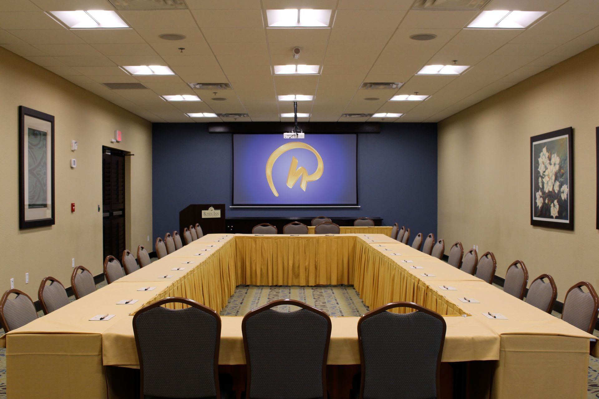 A large meeting room with a long table, chairs, and a projector screen
