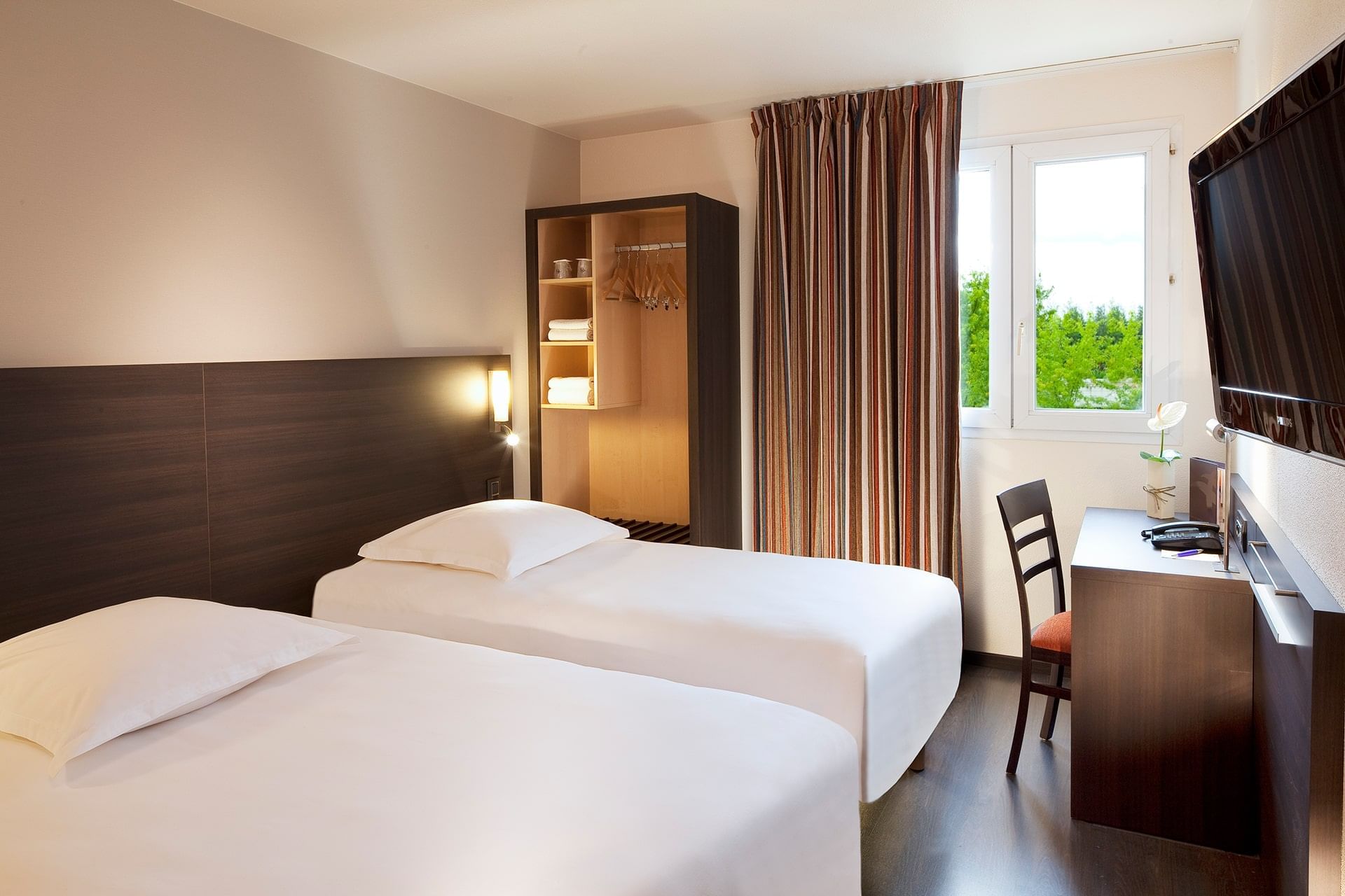 Deux lits et télévision dans une chambre à Escale Oceania Nantes Aeroport