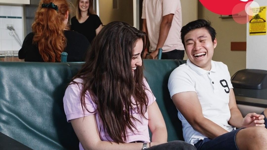 A group of young people socializing in a kitchen, with a slogan 