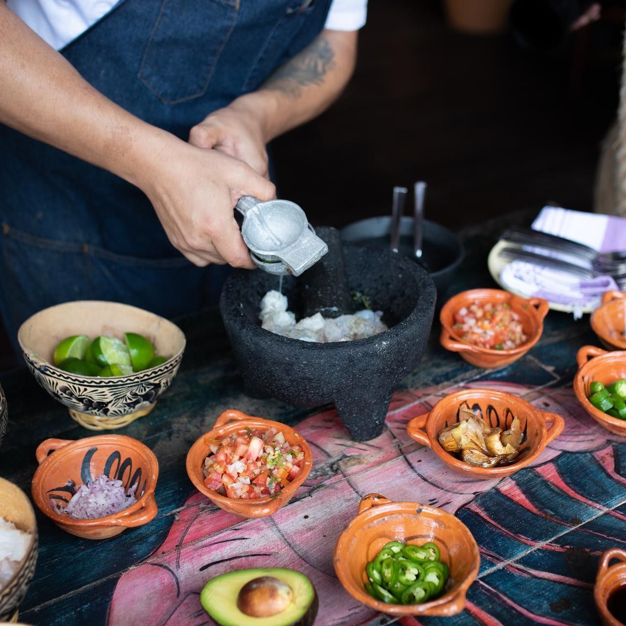 A chef wearing a denim apron prepares fresh ceviche in a molcajete at La Zebra Hotel