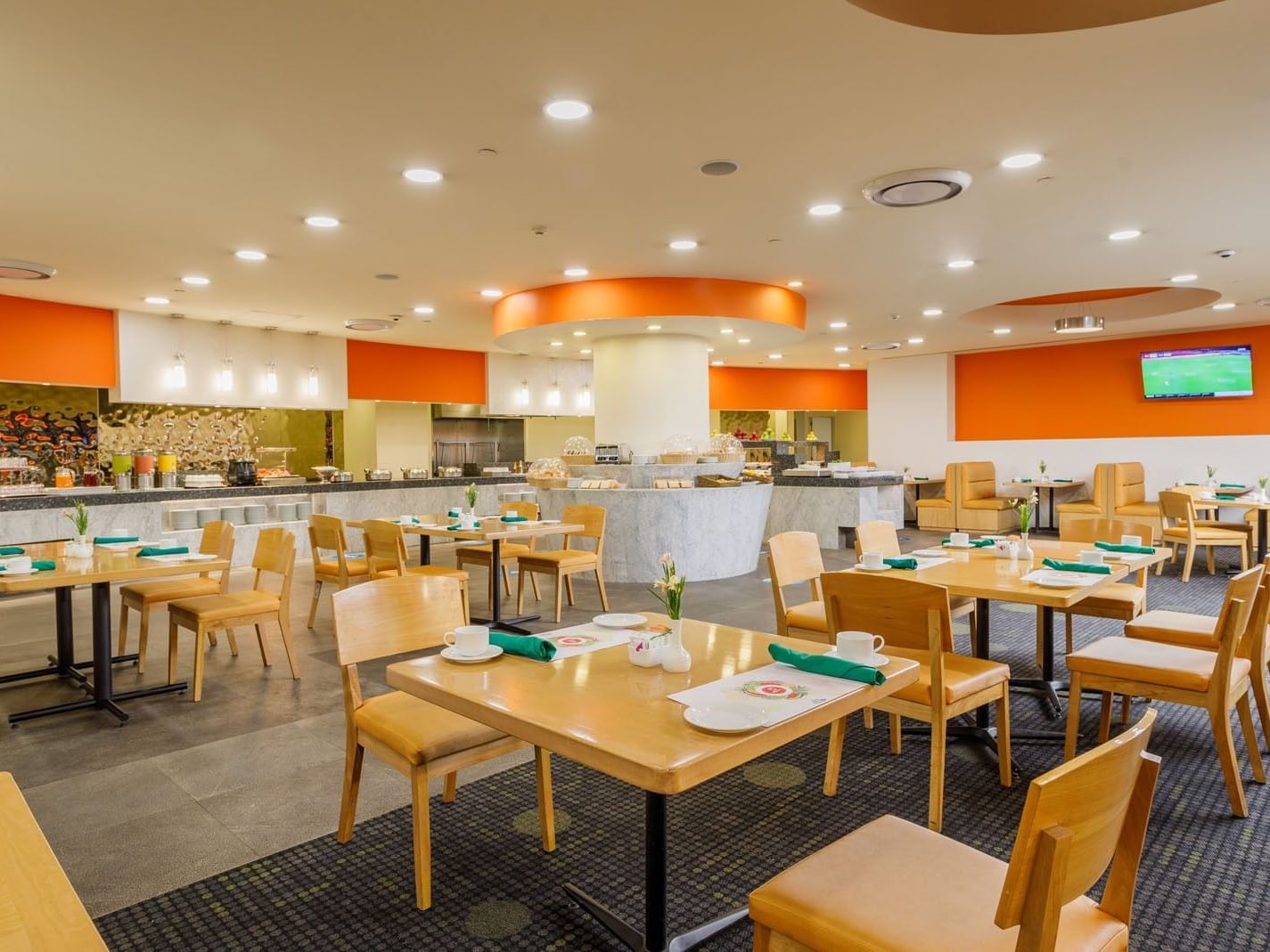 La Huerta breakfast area with wooden tables and orange accent wall decor at Camino Real Aeropuerto Mexico