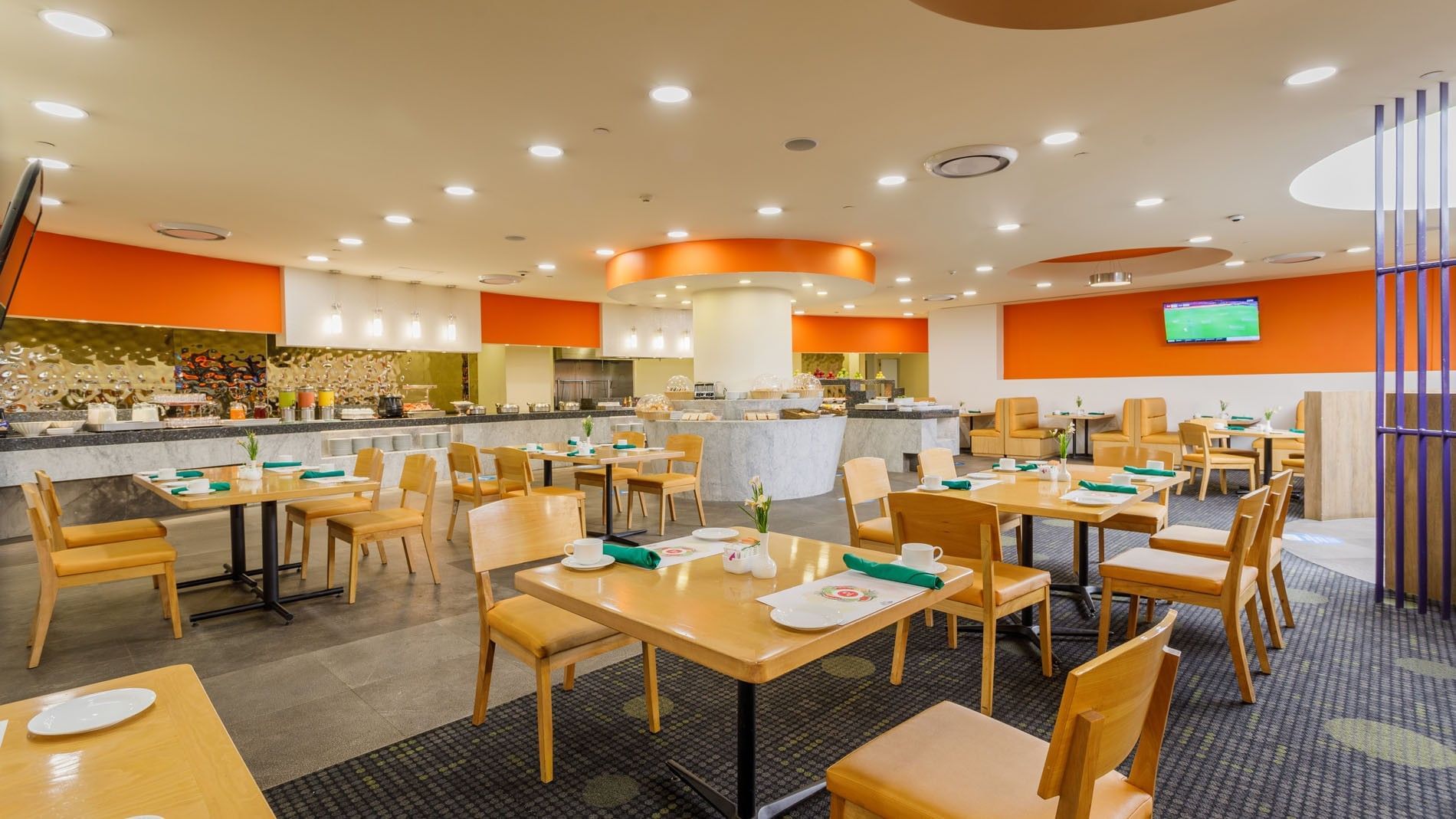 La Huerta breakfast area with wooden tables and orange accent wall decor at Camino Real Aeropuerto Mexico
