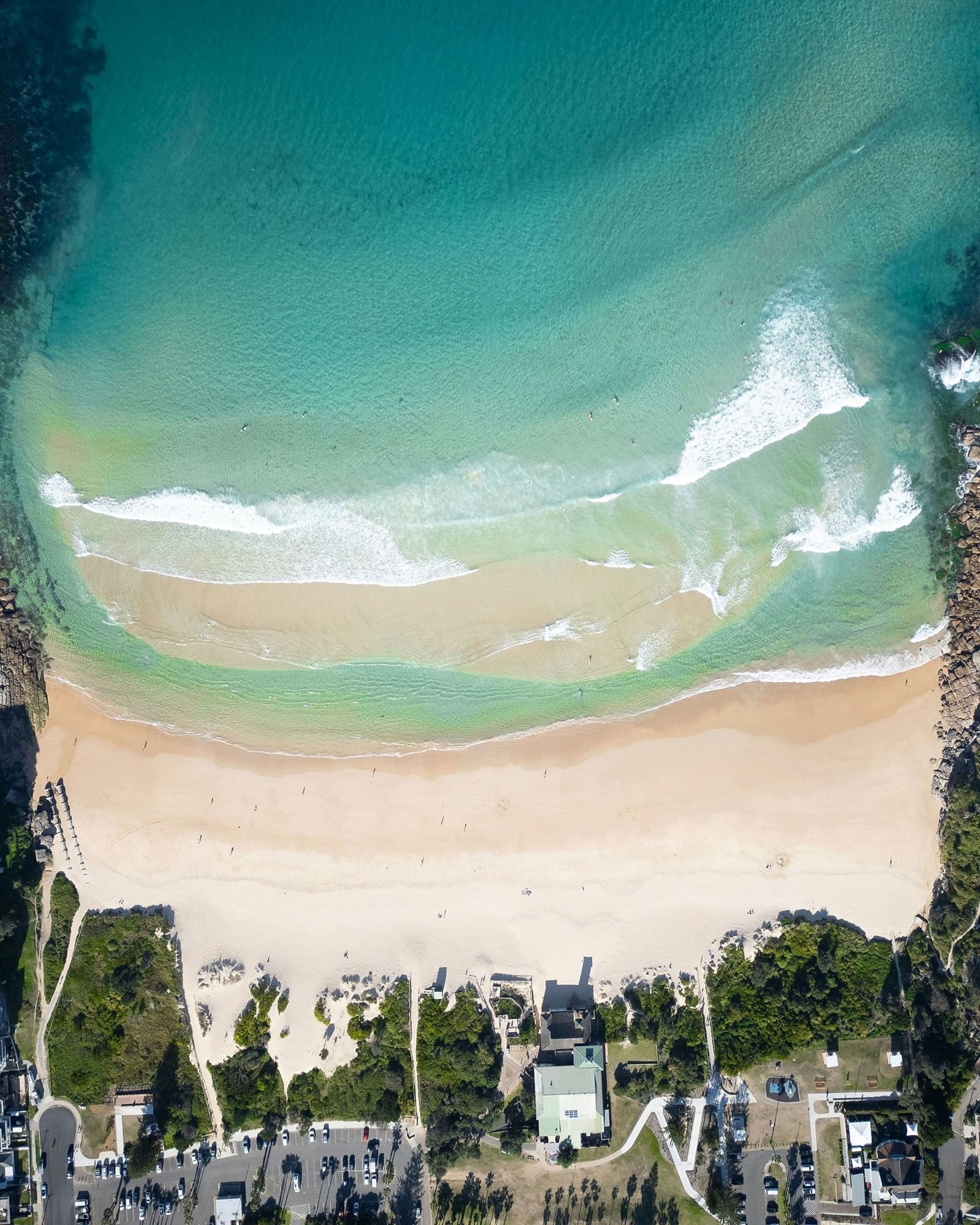 Freshwater Beach at Elysium Hotels has a long sandy shoreline with gentle waves and houses beside a green park