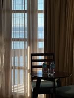 Wooden chairs by a round table with water bottles in front of sheer curtains at Warwick Hotels & Resorts