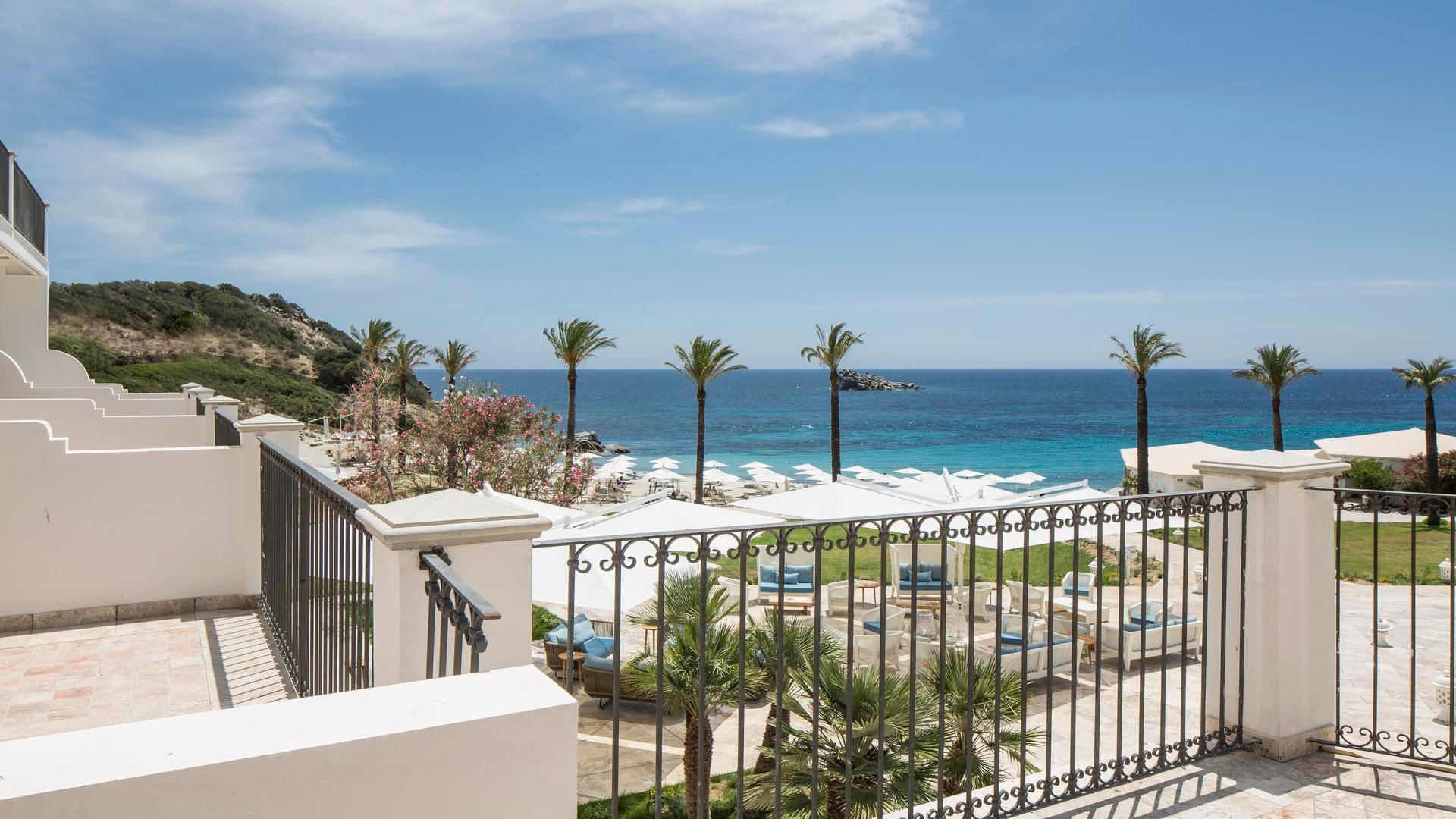 View from a balcony overlooking the ocean & outdoor lounge area at Falkensteiner Resort Capo Boi