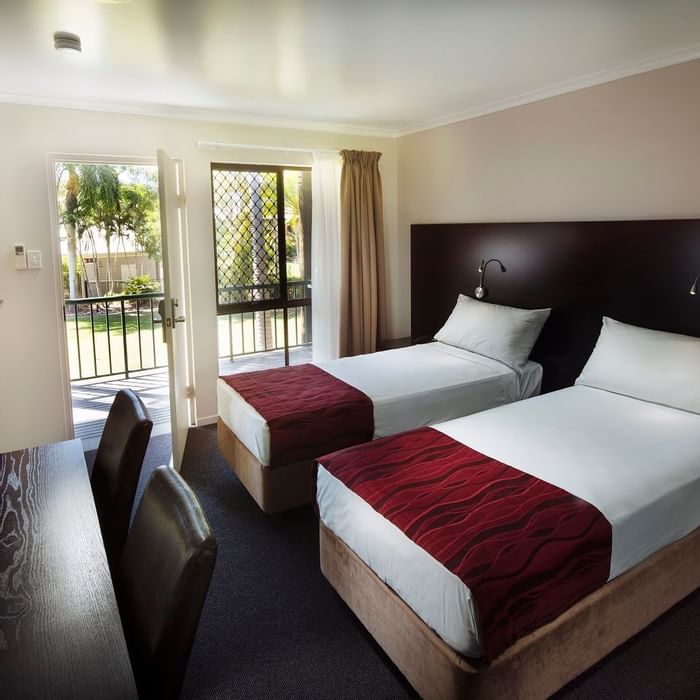 Two twin beds, a desk, and a balcony with garden view in Superior Twin Room at Mercure Hotel Townsville
