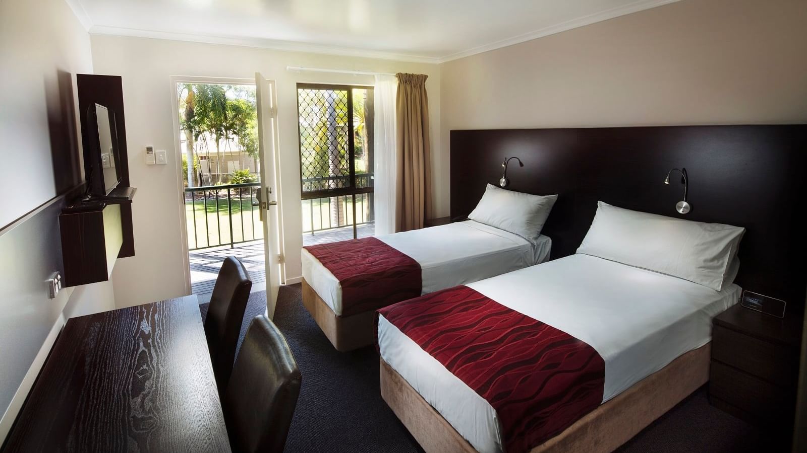 Two twin beds, a desk, and a balcony with garden view in Superior Twin Room at Mercure Hotel Townsville