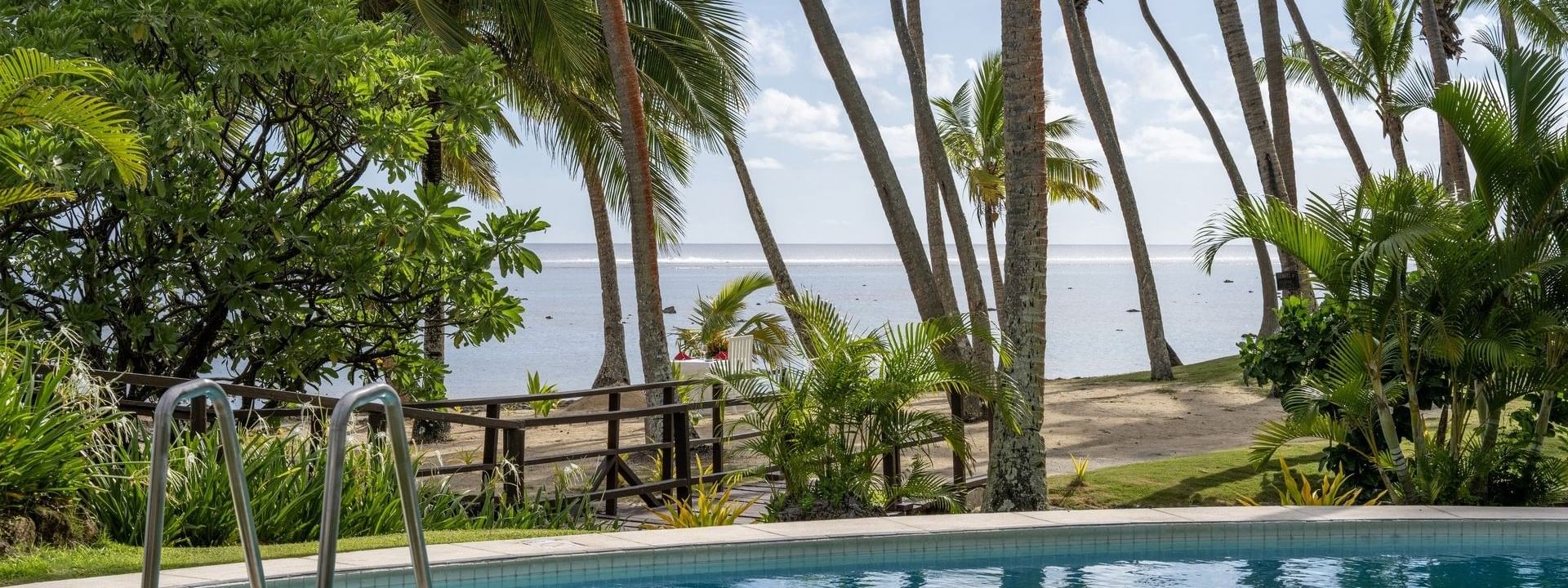 Clear pool surrounded by palm trees and lush greenery at Tambua Sands Beach Resort in Sigatoka