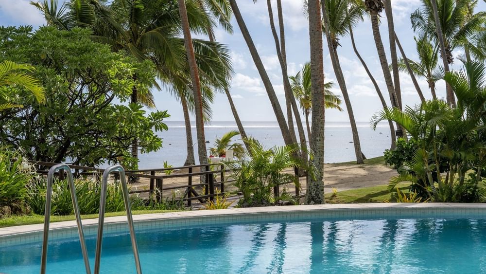 Clear pool surrounded by palm trees and lush greenery at Tambua Sands Beach Resort in Sigatoka.