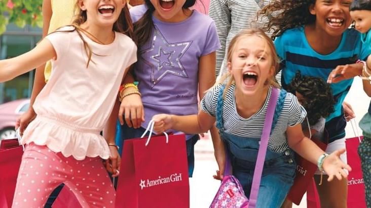 Excited girls holding American Girl shopping bags, enjoying a fun day at Stanford Shopping Center near El Prado Hotel