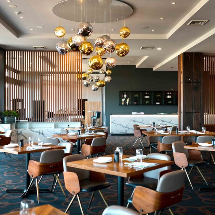 Karinyas Restaurant interior with stylish chairs and tables, pendant lights, and a bar area at Mercure Kooindah Waters