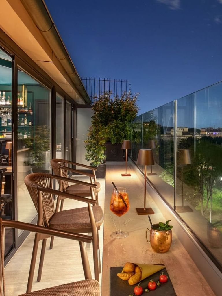 Charming Terrazza Costanza rooftop bar at The Guardian Hotel, with elegant seating and city views under the night sky