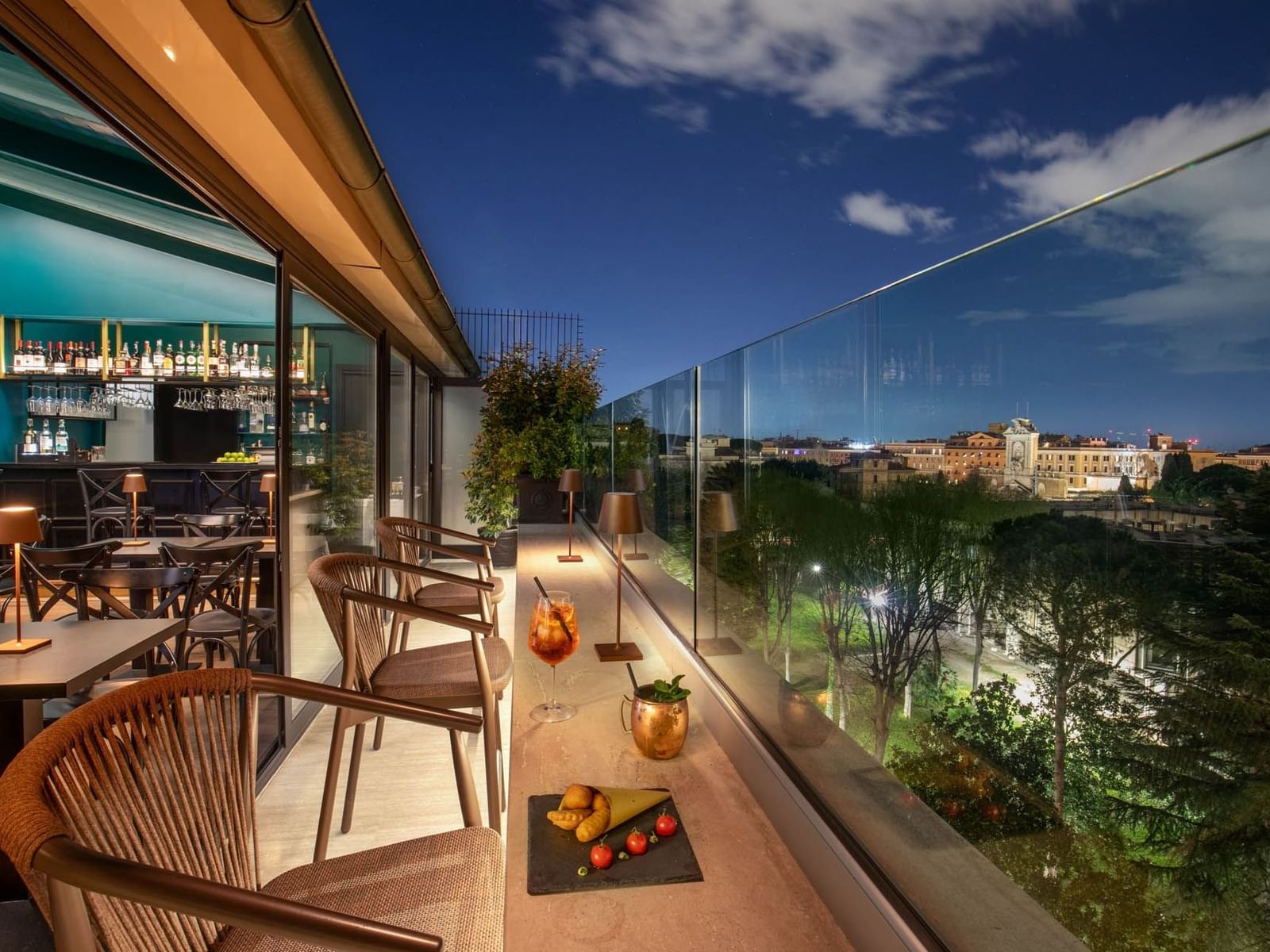 Charming Terrazza Costanza rooftop bar at The Guardian Hotel, with elegant seating and city views under the night sky