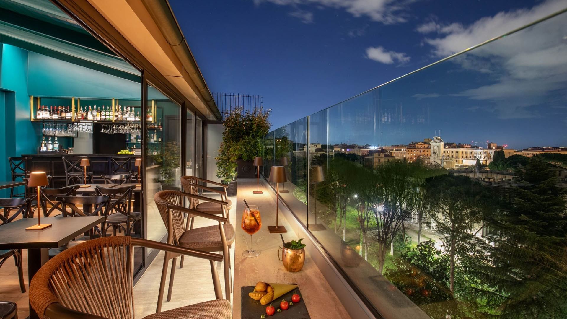 Charming Terrazza Costanza rooftop bar at The Guardian Hotel, with elegant seating and city views under the night sky
