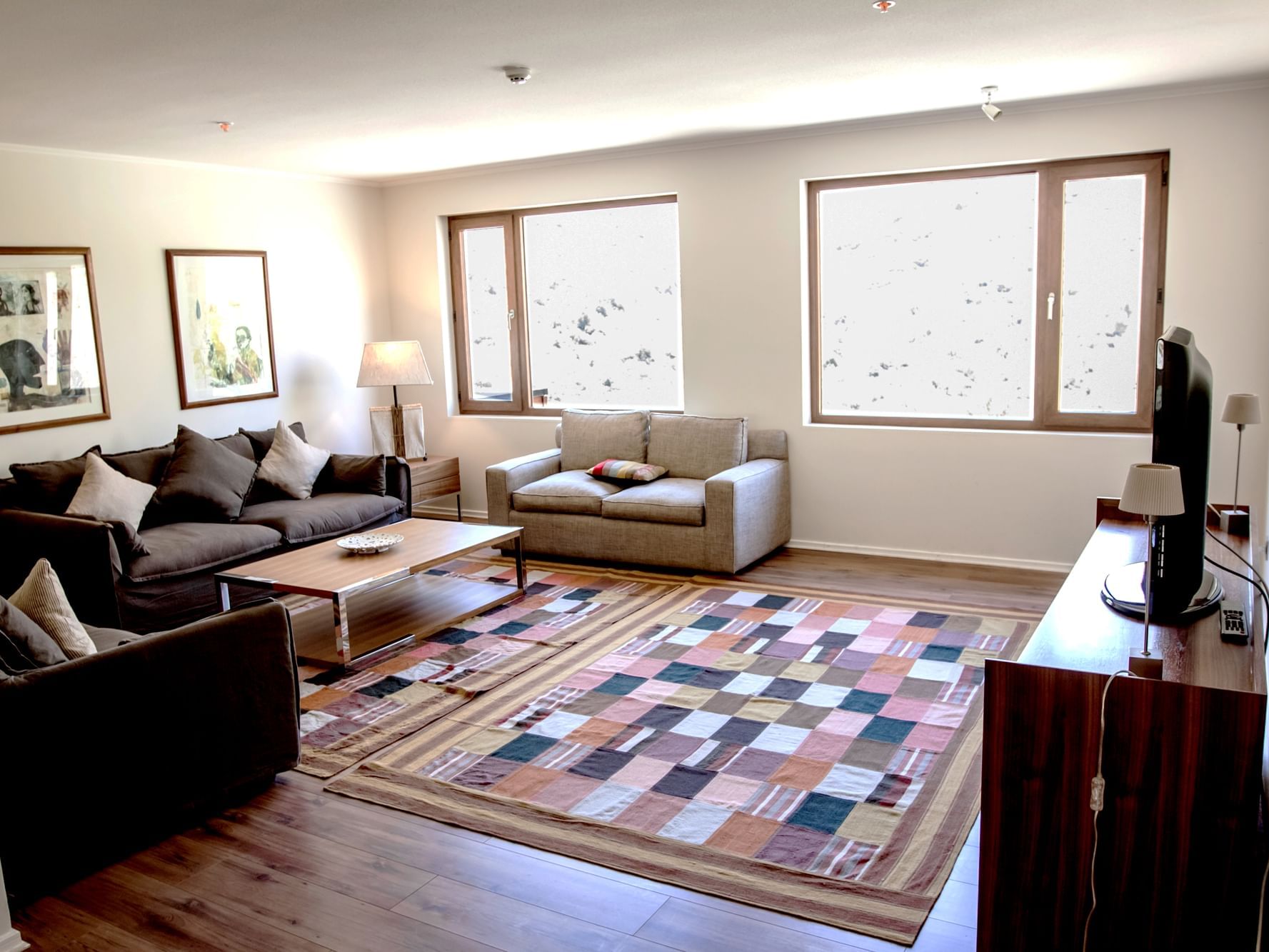 Sala de estar espaçosa com sofás, tapete colorido e janelas amplas no NOI Deluxe Apartamento em Machalí no NOI Puma Lodge.
