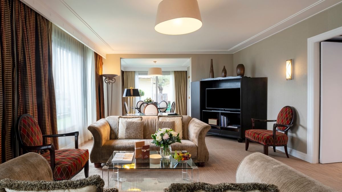 Tan sofas by patterned armchairs under a large pendant light in The Presidential Suite at Warwick Paris Champs Elysées