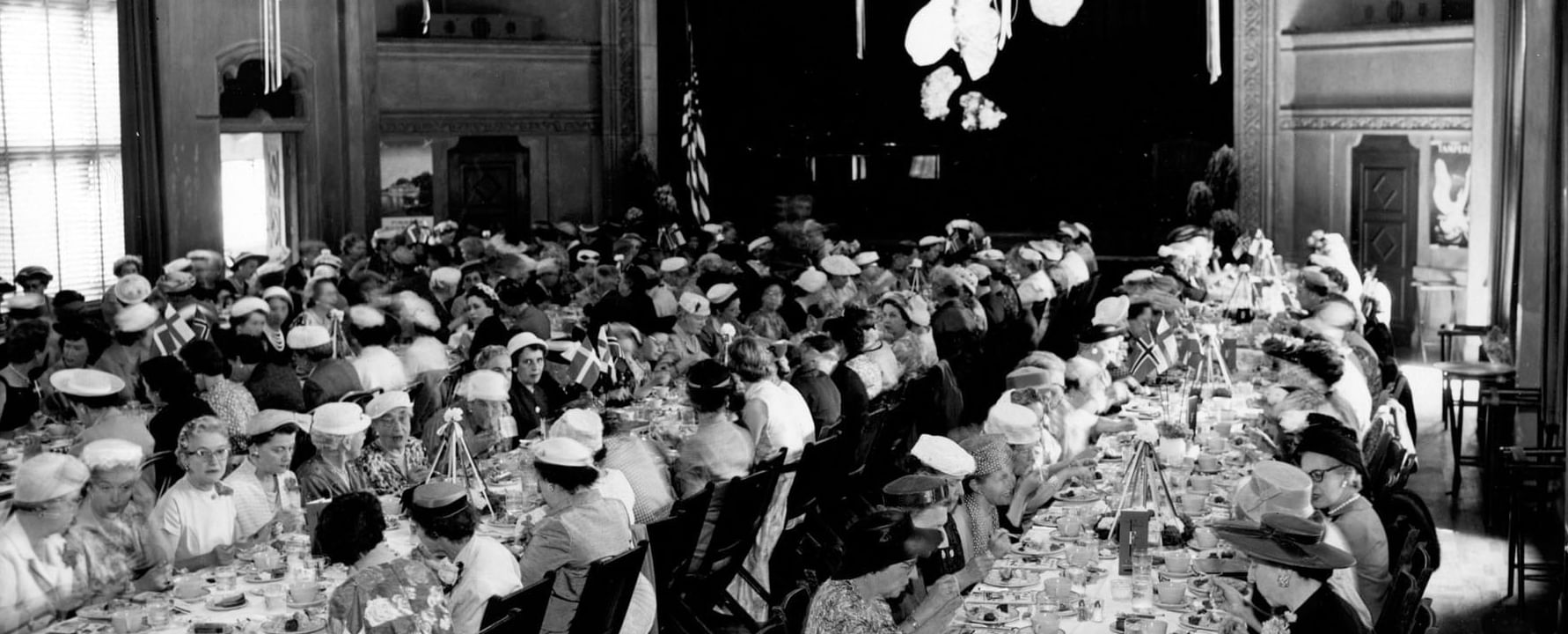 Guests at decorated tables, chandeliers above, in a grand hall at Berkeley City Club