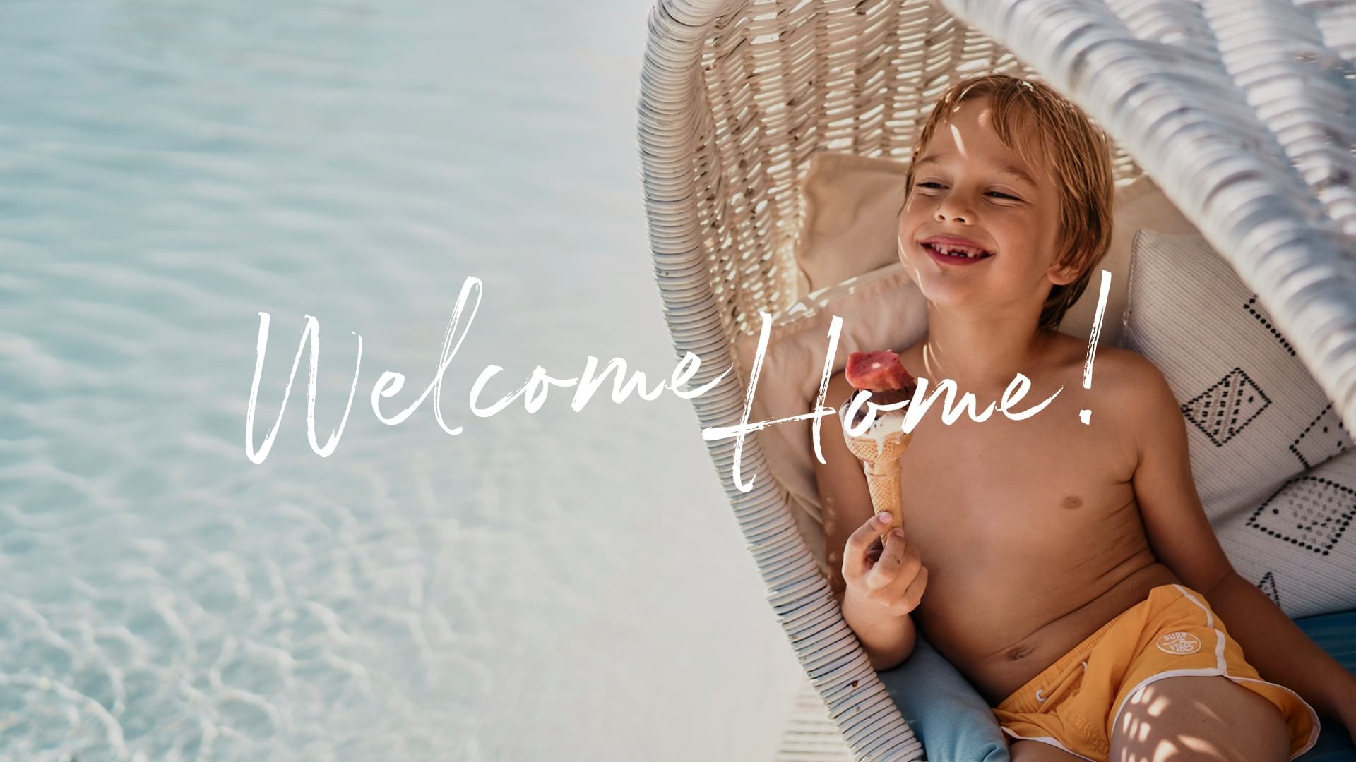 Bambino felice che mangia un gelato su una sedia a sdraio in piscina di Falkensteiner Group