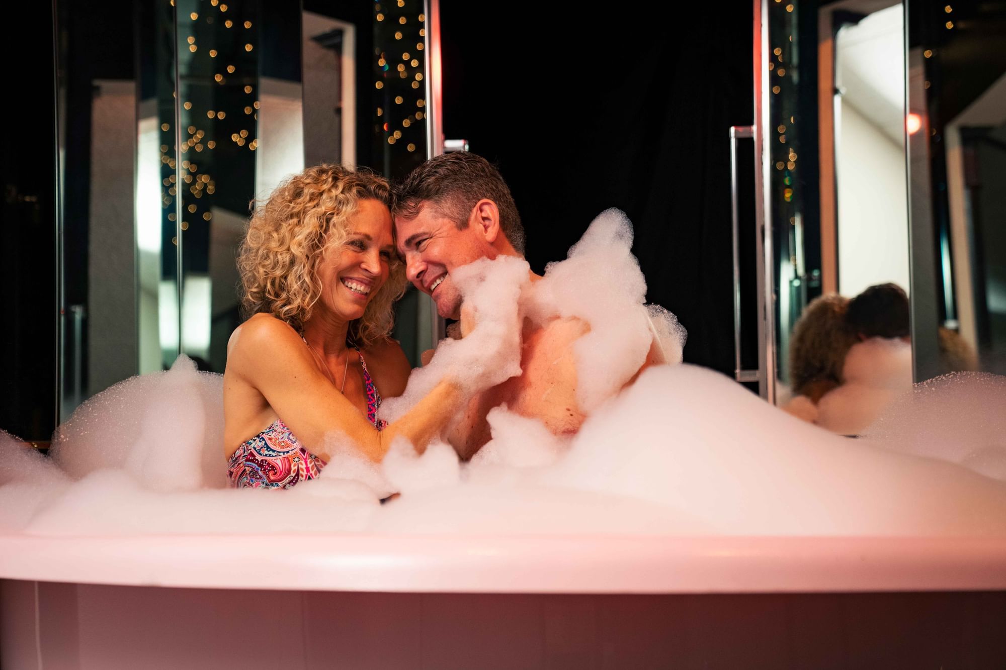 Couple enjoying a romantic moment in the Champagne Tower tub, surrounded by soft lighting at Cove Pocono Resorts