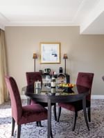 Purple chairs surrounding a round table by a dark desk in The Montaigne Suite at Warwick Paris Champs Elysées