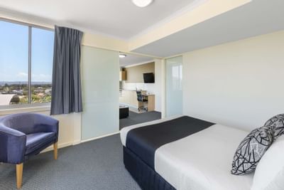 Bed & ancient chair in Two Bedroom Apartment at Nesuto Hotels