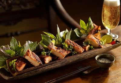 Wooden platter with grilled fish garnished with fresh herbs in Square One at Park Hyatt Saigon