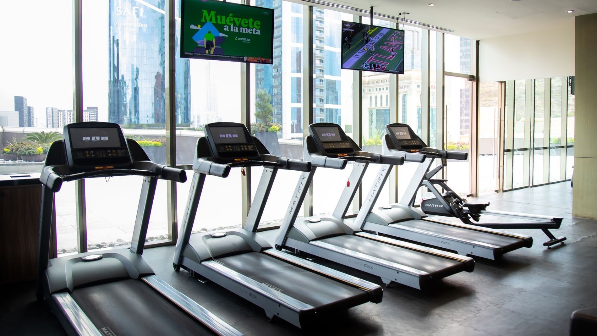 Modern hotel gym with Matrix treadmills facing large windows and city views at Camino Real Fashion Drive, Monterrey