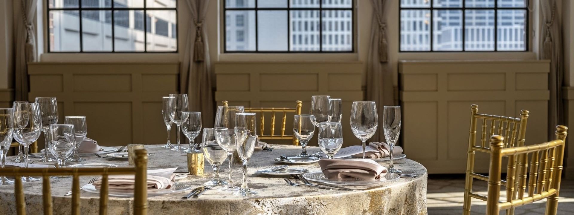 Round dining table with wine glasses, placed by windows in 	
Huron Room at Warwick Allerton Chicago