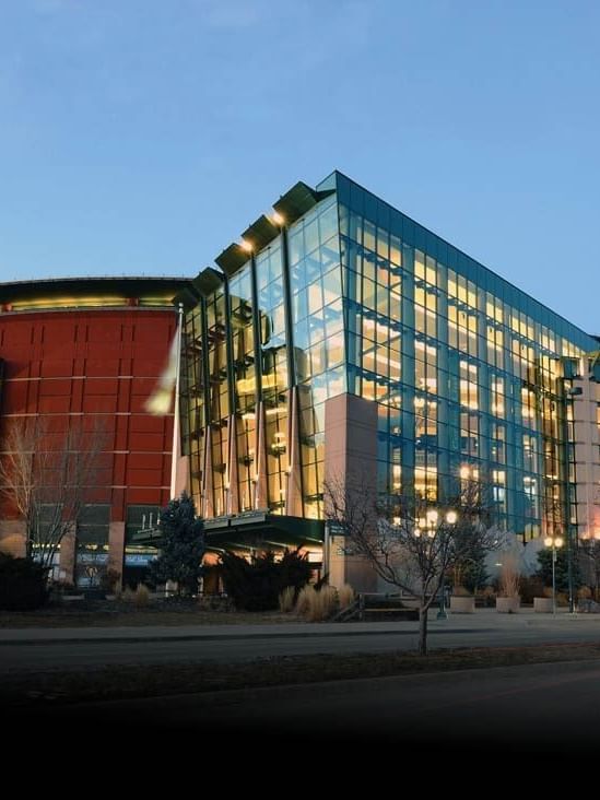 Ball Arena with Glass and brick building with many windows by a street under a clear sky near Warwick Denver