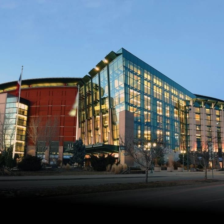 Ball Arena with Glass and brick building with many windows by a street under a clear sky near Warwick Denver