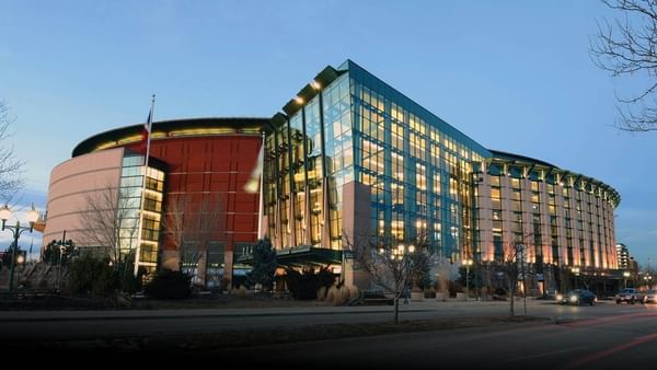 Ball Arena with Glass and brick building with many windows by a street under a clear sky near Warwick Denver