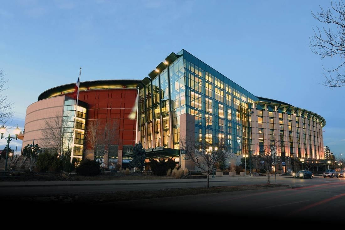 A large, modern hotel building with a curved roof and glass facade, lit up at dusk.