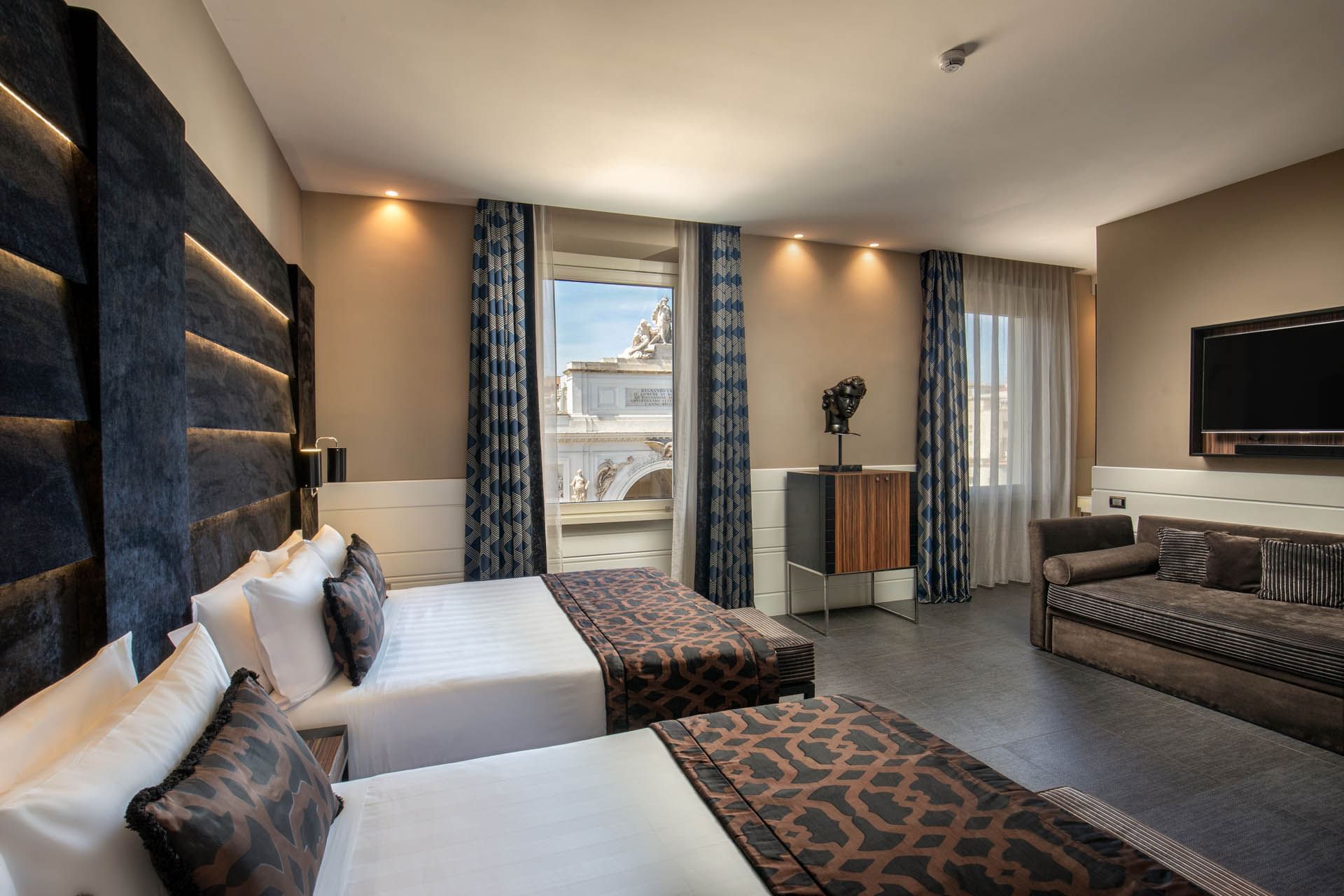 TV with seating facing the bed by the windows in Open Suite at The Glam Hotel