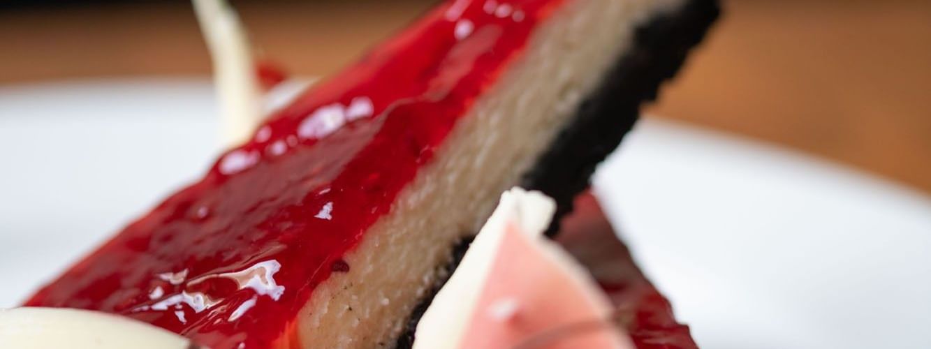 Two slices of cheesecake with a red glaze and dark crust served in the Artist Lobby Lounge at Warwick Hotel Jeddah