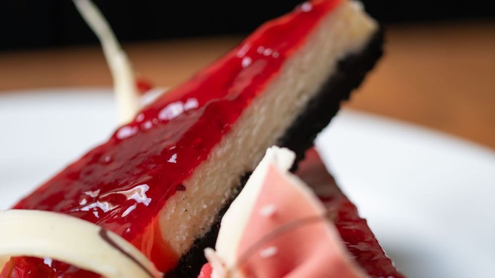 Two slices of cheesecake with a red glaze and dark crust served in the Artist Lobby Lounge at Warwick Hotel Jeddah