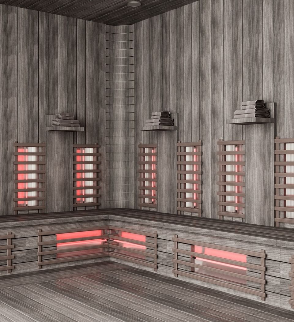 Wooden sauna with red light panels and stacked towels in The LifeCo Wellness Center at A'ila Resorts