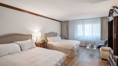 Two beds with tufted headboards & a glass coffee table in the guest room with Sleeper Sofa at Avon Old Farms Hotel